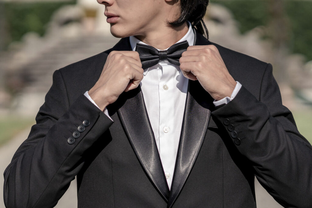 Groom model adjusting his black bow tie.