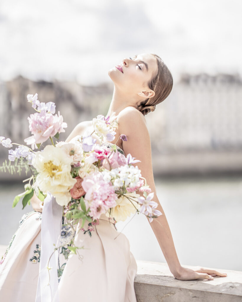 Bridal photoshoot with bride holding large fresh floral bouquet and looking up to the sky.