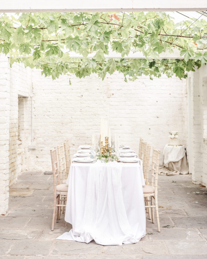 A wedding dinner table set up with candles and dinnerware in the Orangery at Garthmyl Hall during a wedding shoot.